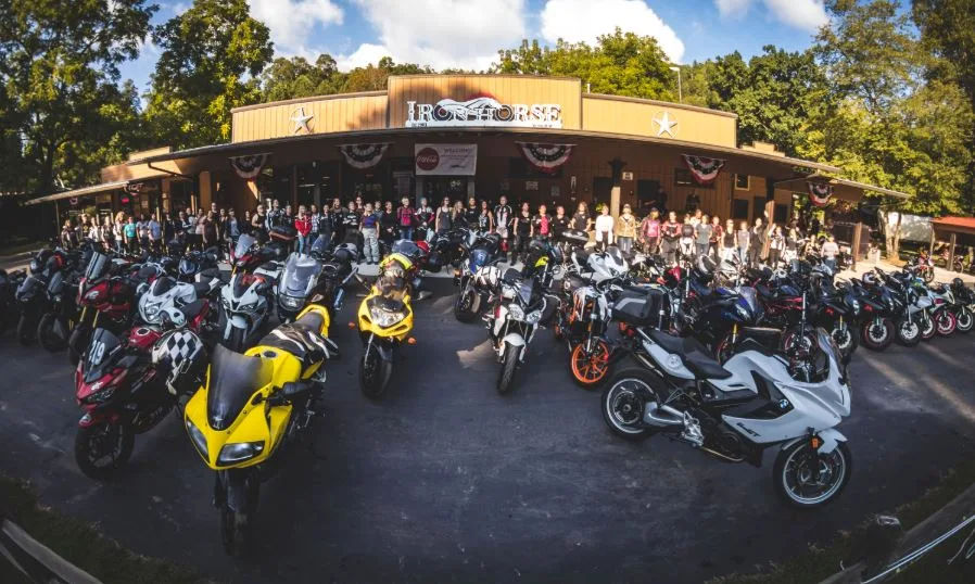 Rows of motorcycles lined up outside a dealership with a crowd gathered